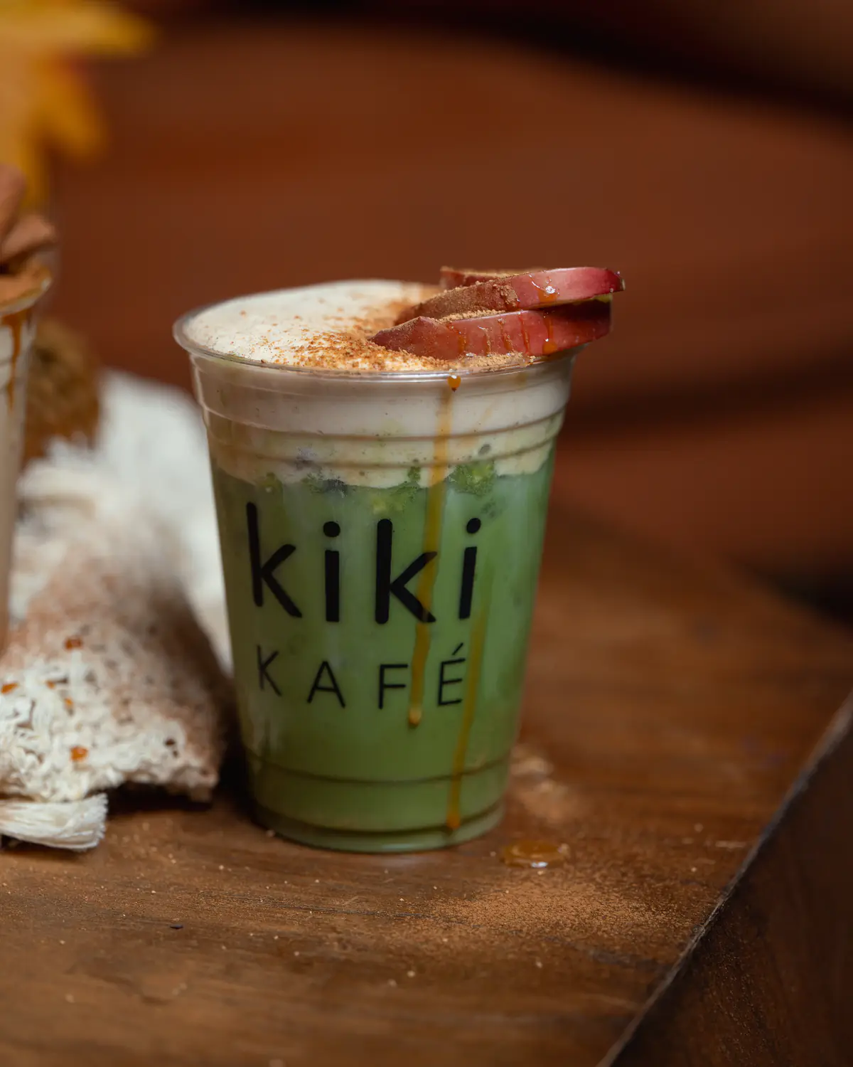 Caramelized apple matcha from the Kiki Kafé fall 2026 menu, topped with apple slices and cinnamon