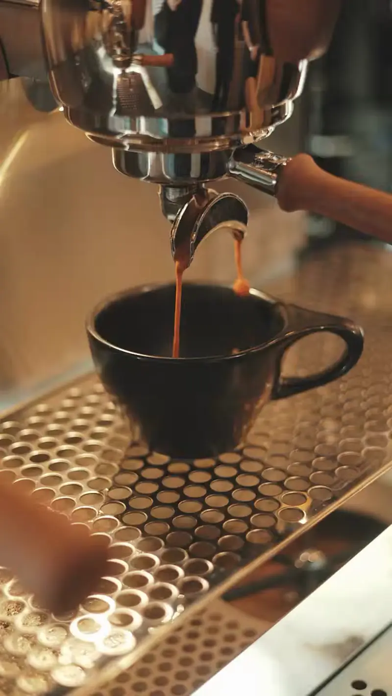 Espresso pouring into a black cup at Kiki Kafé