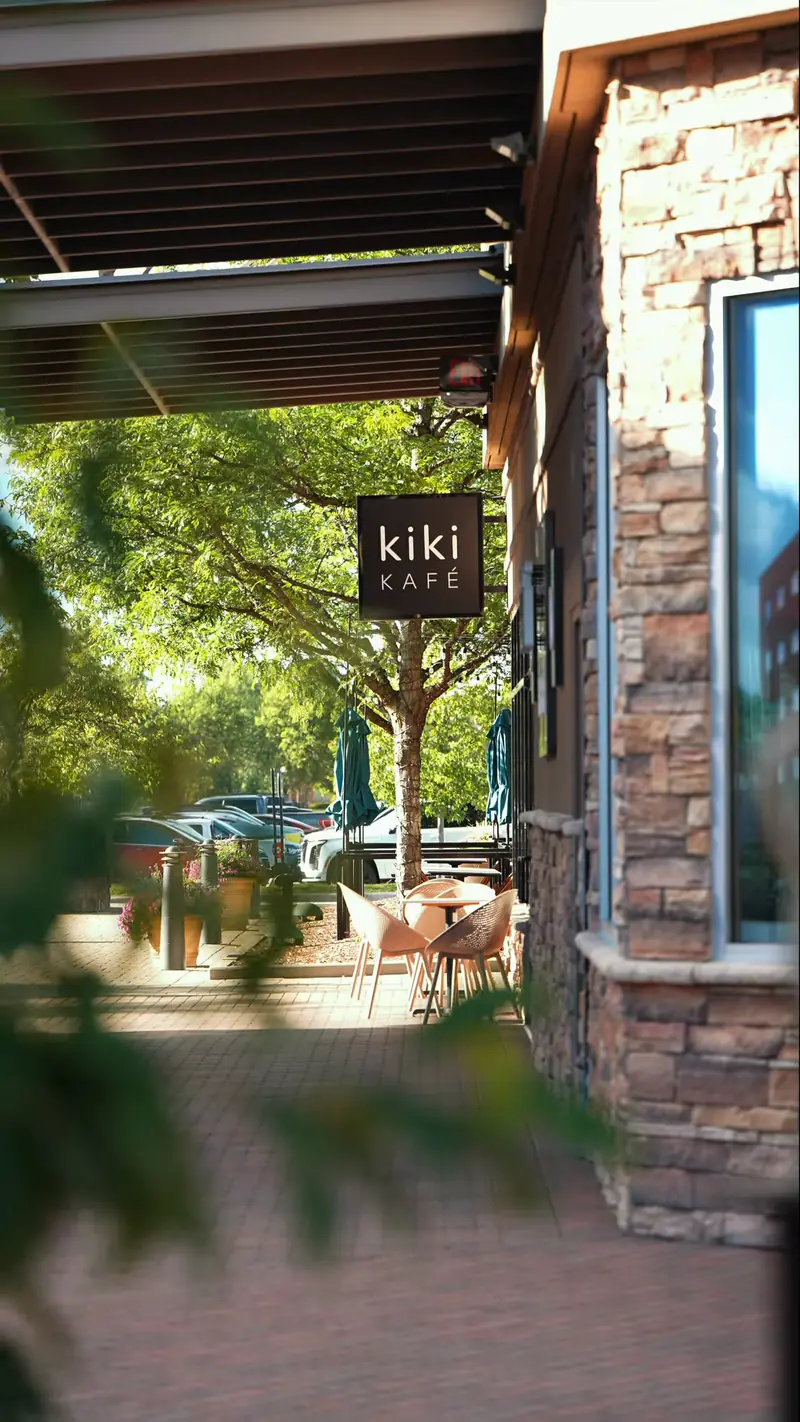 Kiki Kafé blade sign and outdoor patio on the tree-lined walk at Partridge Creek