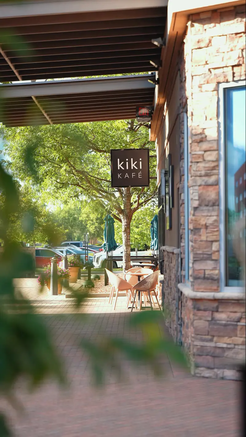 Kiki Kafé sign and patio tables on a summer day at Partridge Creek