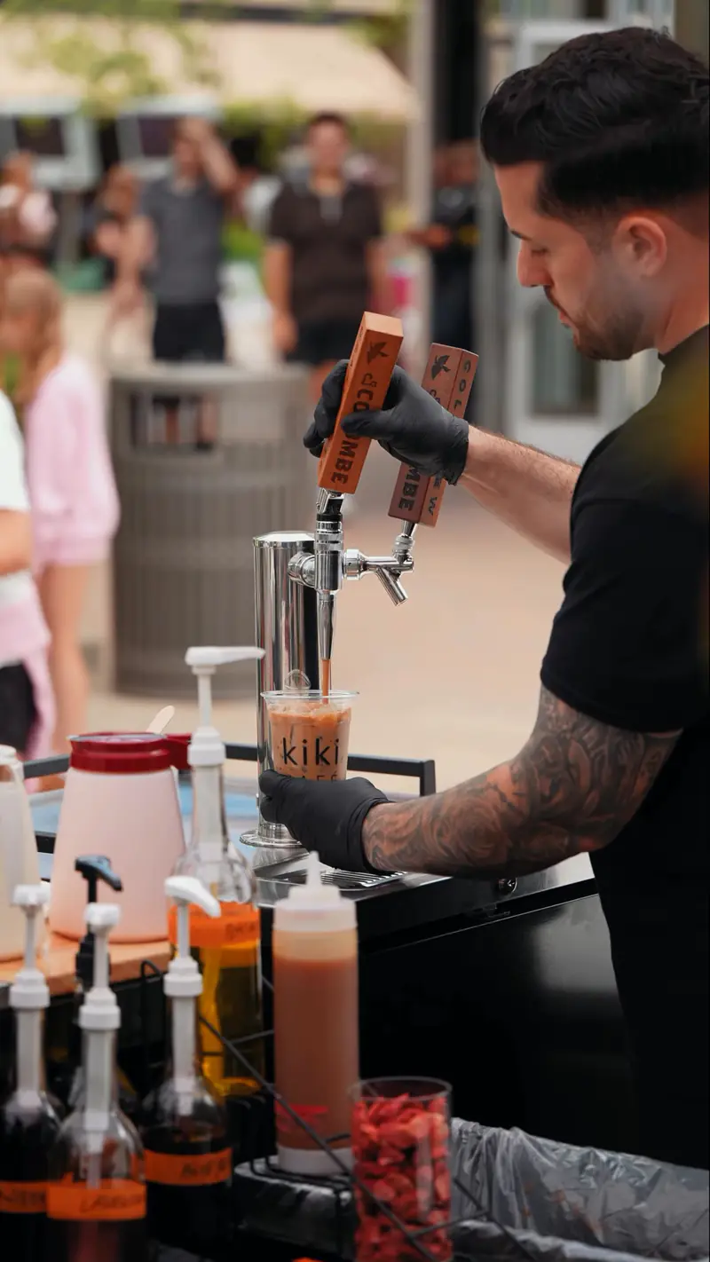 Kiki barista pouring from nitro cold brew taps at the Kiki Kart coffee cart during an outdoor concert