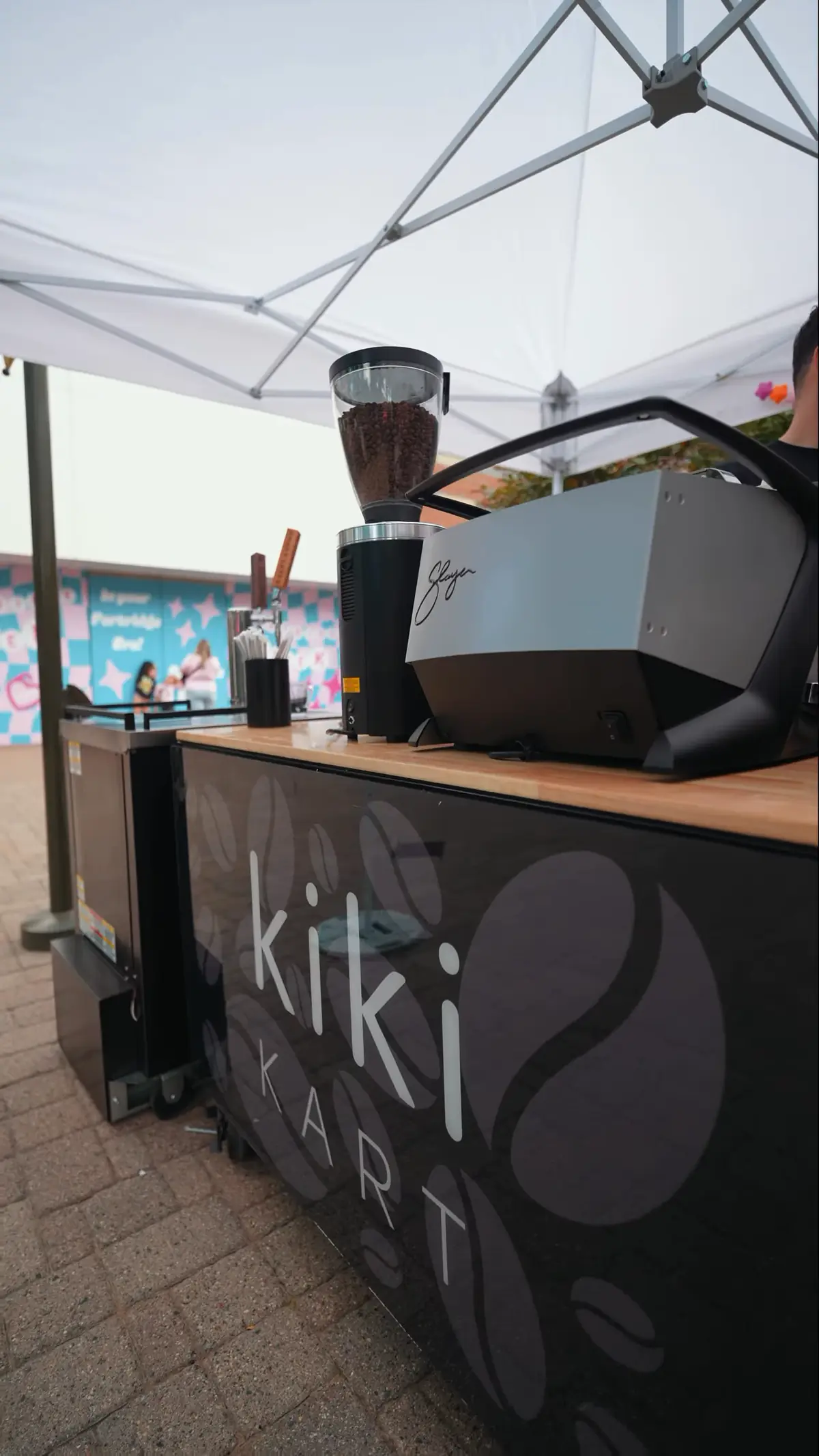 The Kiki Kart coffee cart and mobile espresso bar set up under a white event tent