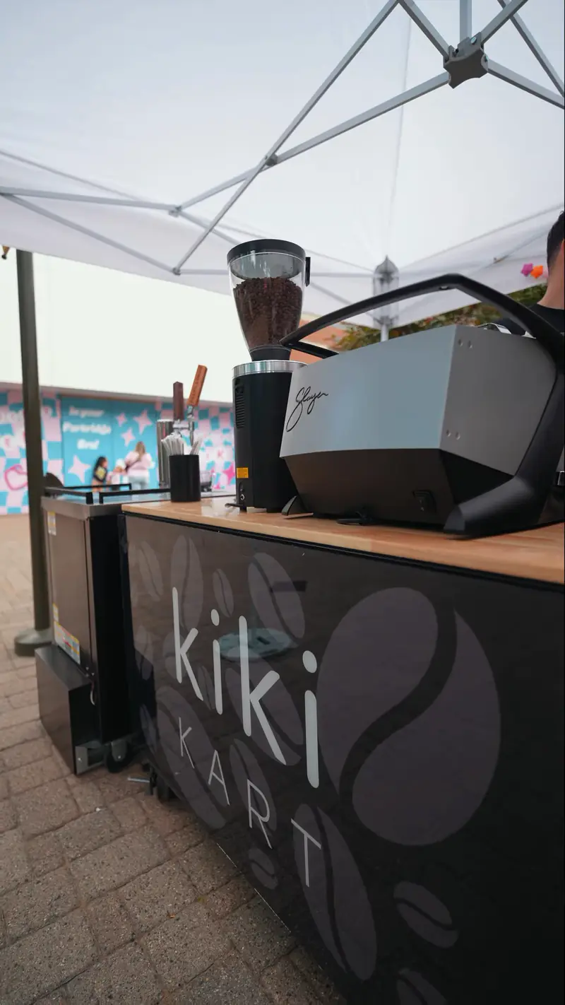The Kiki Kart coffee cart and mobile espresso bar set up under a white event tent