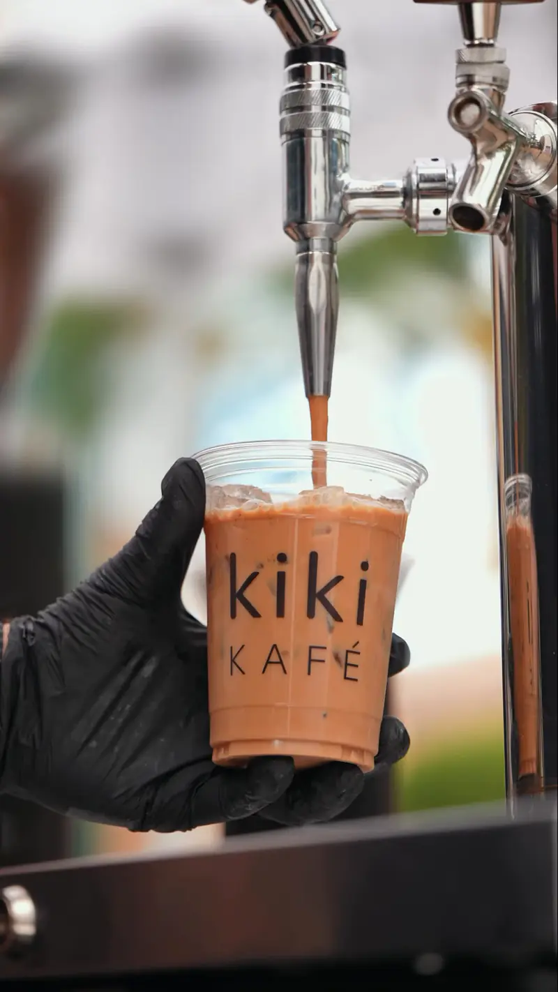 Nitro cold brew pouring from a tap into a Kiki Kafé cup