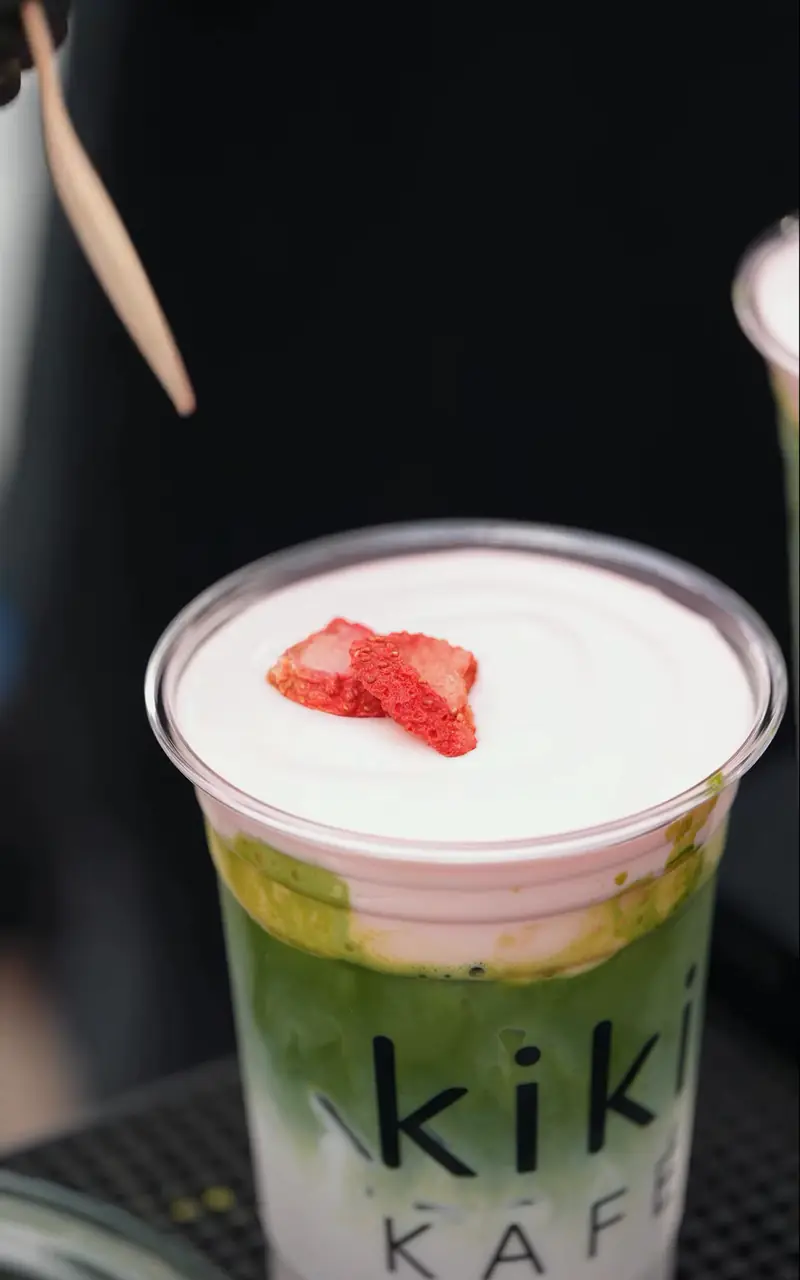 Strawberry cream matcha topped with fresh strawberry in a Kiki Kafé cup