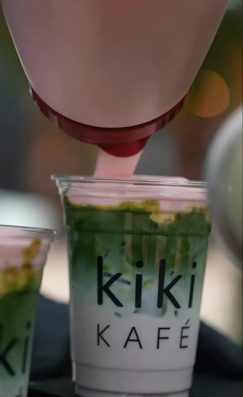 Strawberry cream poured over an iced matcha in a Kiki Kafé cup